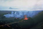 Surtsey 27. srpna 1966. Proudy lávy ze tří malých sopečných kuželů. Erupce začala v listopadu 1963 a rychle se vytvořil nový ostrov, od dubna 1964 s výrony lávy. Erupce pokračovaly až do r. 1967. Malý ostrov Jolnir v pozadí vznikal 800 m jihozápadně od Surtsey od konce října 1965 a procházel opakovanými epizodami růstu a destrukce, v říjnu 1966 působením eroze zanikl. Foto R. Williams, U.S. Geological Survey